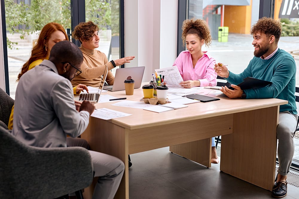 Group of business people meeting at office for analyzing data by using laptop and discussing for planning strategy and brainstorming for new project, dressed in stylish formal clothes, in boardroom